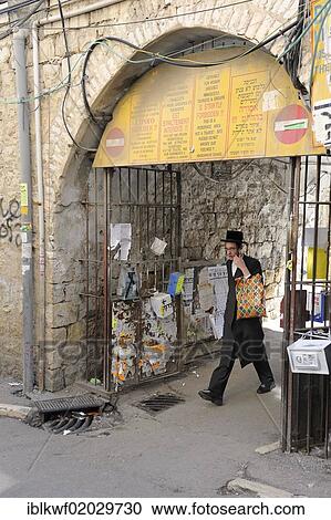 Stock Image - Sign prohibiting the entry of non-Orthodox Jews in a residential housing estate, with an Orthodox Jew leaving through the gateway, in the district of Me'a She'arim or Mea Shearim, Jerusalem, Israel, Middle East, Asia. Fotosearch