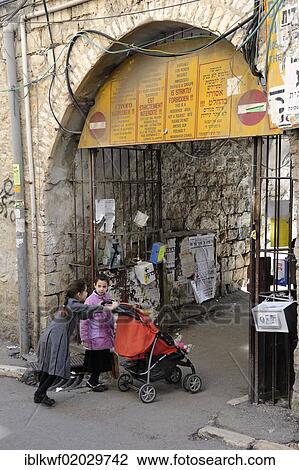Stock Image - Sign prohibiting the entry of non-Orthodox Jews in a residential housing estate, with jewish children entering through the gateway, in the district of Me'a She'arim or Mea Shearim, Jerusalem, Israel, Middle East, Asia. Fotosearch