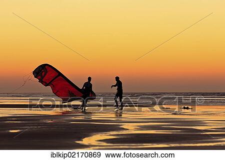Silhouettes of two men walking on the beach with a kite surfer sail at sunset, Essaouira, Morocco, Africa View Large Photo Image Stock Photo - Silhouettes of two men walking on the beach with a kite surfer sail at sunset, Essaouira, Morocco, Africa. Fotosearch