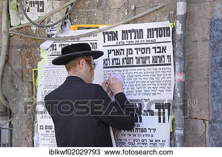 Stock Image - Street scene with an Orthodox Jew in the Me'a She'arim district, with typical wall newspapers, Jerusalem, Israel, Middle East, Asia. Fotosearch
