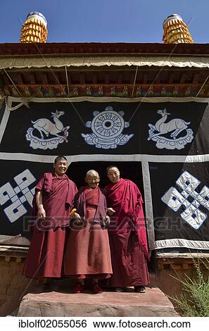 Three Buddhist nuns, one young nun, one middle-aged nun and one elderly nun, over 70 years, wearing red robes in front of the Tibetan Buddhist symbols at the monastery entrance, Gongkar Chode monastery, Lhasa, Tibet, China, Asia View Large Photo Image Stock Photograph - Three Buddhist nuns, one young nun, one middle-aged nun and one elderly nun, over 70 years, wearing red robes in front of the Tibetan Buddhist symbols at the monastery entrance, Gongkar Chode monastery, Lhasa, Tibet, China, Asia. Fotosearch