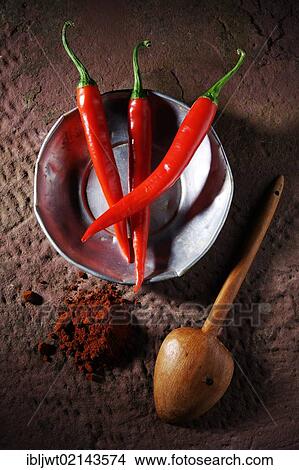 Three Chili Peppers (Capsicum) on a tin plate with a wooden spoon and chili powder on a rustic stone surface View Large Photo Image Picture - Three Chili Peppers (Capsicum) on a tin plate with a wooden spoon and chili powder on a rustic stone surface. Fotosearch