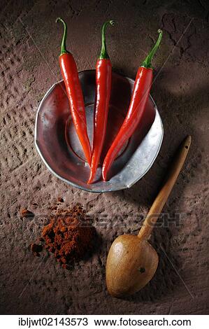 Three Chili Peppers (Capsicum) on a tin plate with a wooden spoon and chili powder on a rustic stone surface View Large Photo Image Stock Image - Three Chili Peppers (Capsicum) on a tin plate with a wooden spoon and chili powder on a rustic stone surface. Fotosearch
