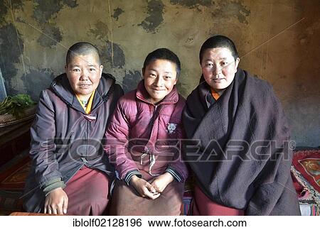 Stock Photograph - Three Tibetan nuns sitting in the kitchen of the nunnery in the mountains of Reting Monastery, Mount Gangi Rarwa, Himalayas, Lhundrup Country, Central Tibet, Tibet, Asia. Fotosearch