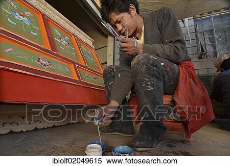 Stock Photography - Tibetan handicrafts, carpenter painting a typical Tibetan wooden cabinet with red paint and ornaments, lacquer work, Tibet, China, Asia. Fotosearch