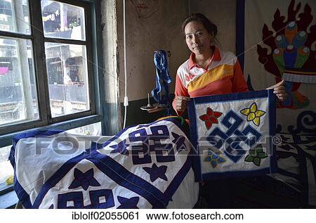 Stock Image - Tibetan handicrafts, dressmaker with Buddhist symbols on textiles, textile art, Tibet, Lhasa, China, Asia. Fotosearch