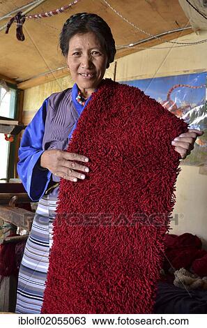 Stock Image - Tibetan woman wearing traditional costume, yak wool weaver holding red yak wool, Tibetan handicrafts, Lhasa, Tibet, China, Asia. Fotosearch
