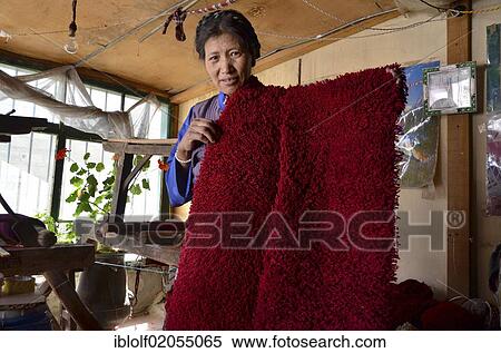 Stock Photography - Tibetan woman wearing traditional costume, yak wool weaver holding red yak wool, Tibetan handicrafts, Lhasa, Tibet, China, Asia. Fotosearch