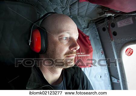 Stock Photo - Tourist wearing ear protection, Air Greenland helicopter, Tasiilaq, Ammassalik Peninsula, East Greenland, Greenland, North America. Fotosearch