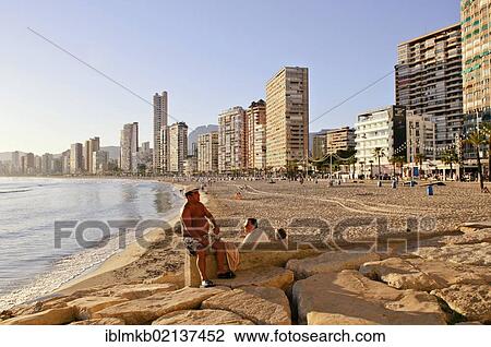 Stock Image - Tourists in the evening light at Playa Levante beach, Benidorm, Spain, Europe. Fotosearch