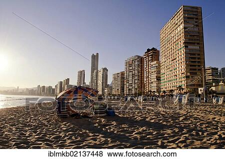 Stock Photo - Tourists sitting under a beach sunshade on Playa Levante beach, Benidorm, Spain, Europe. Fotosearch