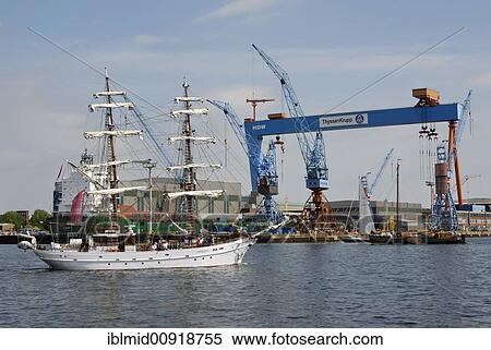 Stock Photography - Traditional sailing boats in front of the crane of the Howaldtswerke-German-Shipyard, HDW, in the Kiel inner Fjord, Kiel Week 2008, Kiel, Schleswig-Holstein, Germany, Europe. Fotosearch