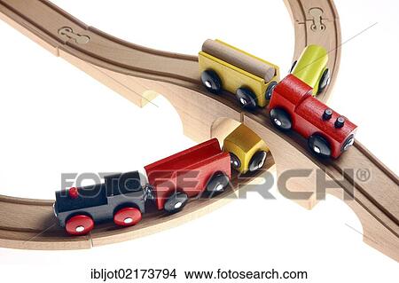 Picture - Two toy wooden trains crossing each other at a railroad crossing, railway bridge. Fotosearch