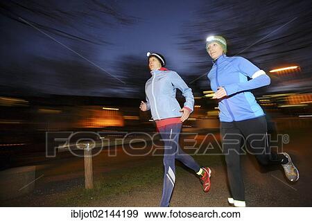 Two young women jogging at dusk in winter clothing with reflective strips, LED headlights and wind and waterproof functional clothing, Germany, Europe View Large Photo Image Stock Photo - Two young women jogging at dusk in winter clothing with reflective strips, LED headlights and wind and waterproof functional clothing, Germany, Europe. Fotosearch