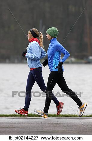 Two young women jogging in winter, wearing wind and waterproof performance apparel View Large Photo Image Stock Photo - Two young women jogging in winter, wearing wind and waterproof performance apparel. Fotosearch