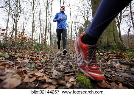 Stock Photo - Two young women jogging through a forest in winter, wearing wind and waterproof performance apparel. Fotosearch