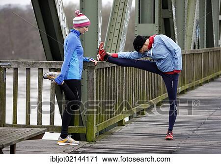 Two young women stretching after jogging in winter, wearing wind and waterproof performance apparel View Large Photo Image Stock Image - Two young women stretching after jogging in winter, wearing wind and waterproof performance apparel. Fotosearch