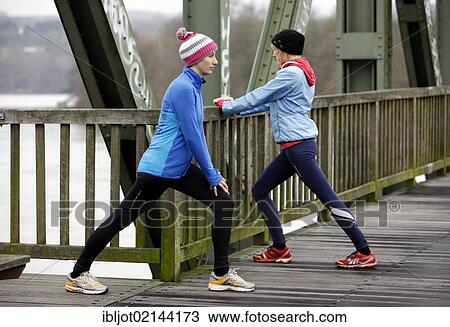 Two young women stretching after jogging in winter, wearing wind and waterproof performance apparel View Large Photo Image Stock Image - Two young women stretching after jogging in winter, wearing wind and waterproof performance apparel. Fotosearch