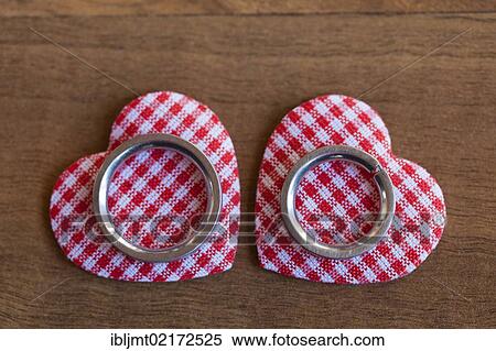 Wedding rings lying on two red and white checkered hearts View Large Photo Image Stock Photography - Wedding rings lying on two red and white checkered hearts. Fotosearch