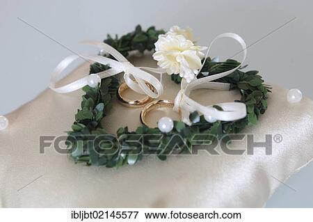Wedding rings on a pillow decorated with a heart View Large Photo Image Stock Photo - Wedding rings on a pillow decorated with a heart. Fotosearch