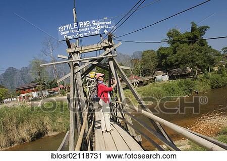 Woman walking across a wooden bridge over the Nam Song River, Vang Vieng, Vientiane, Laos, Indochina, Asia View Large Photo Image Stock Image - Woman walking across a wooden bridge over the Nam Song River, Vang Vieng, Vientiane, Laos, Indochina, Asia. Fotosearch