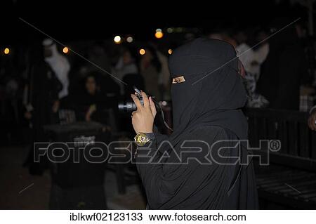 Stock Image - Woman wearing a hijab, head and body covering, taking photographs, Schindagha, Dubai, United Arab Emirates, Arabia, Arabian Peninsula, Asia. Fotosearch