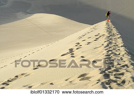 Young Chinese woman standing on the sand dunes of the Gobi Desert while photographing the Crescent Lake with the Chinese Pagoda in Dunhuang, Silk Road, Gansu, China, Asia View Large Photo Image Stock Image - Young Chinese woman standing on the sand dunes of the Gobi Desert while photographing the Crescent Lake with the Chinese Pagoda in Dunhuang, Silk Road, Gansu, China, Asia. Fotosearch