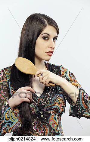 Stock Image - Young woman brushing her hair. Fotosearch