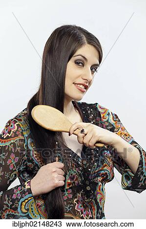 Stock Image - Young woman brushing her hair. Fotosearch