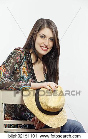 Stock Image - Young woman holding a hat in her hand. Fotosearch