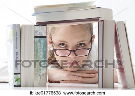 Stock Photo - Young woman with glasses looking through a stack of books. Fotosearch