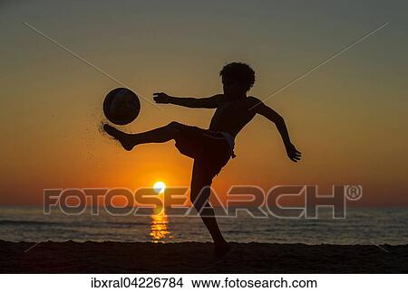Boy with soccer ball, sunset at the sea, beach, Italy, Europe View Large Photo Image Picture - Boy with soccer ball, sunset at the sea, beach, Italy, Europe. Fotosearch