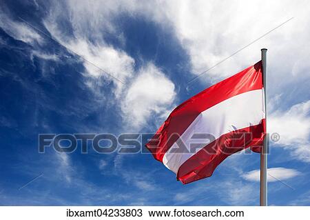 Stock Image - Flag of Austria against blue sky with white clouds. Fotosearch