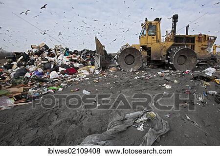 Stock Photo - A bulldozer levels and compacts garbage at St. Clair County's Smith's Creek Landfill; landfill operators collect methane from decaying refuse and burn it to generate electricity, Smith's Creek, Michigan, USA, North America. Fotosearch