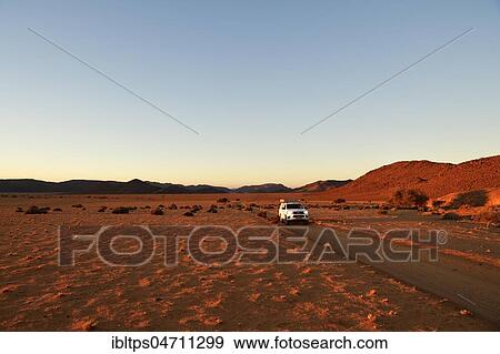 All-terrain vehicle drives on sandtrack in the evening light, behind Tiras Mountains, Namibia, Africa View Large Photo Image Stock Photo - All-terrain vehicle drives on sandtrack in the evening light, behind Tiras Mountains, Namibia, Africa. Fotosearch