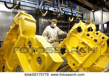 An employee of the Luitpoldhuette AG, a foundry that specializes in the casting of engine blocks, motor parts and refrigeration compressors, controlling the priming of cast parts in a colour dip, in Amberg, Bavaria, Germany, Europe View Large Photo Image Stock Photo - An employee of the Luitpoldhuette AG, a foundry that specializes in the casting of engine blocks, motor parts and refrigeration compressors, controlling the priming of cast parts in a colour dip, in Amberg, Bavaria, Germany, Europe. Fotosearch