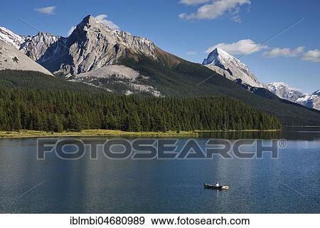 Stock Photo - Angler on Maligne Lake, behind it mountain range, Jasper National Park, Rocky Mountains, Alberta, Canada, North America. Fotosearch