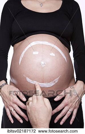 Stock Image - Baby belly with painted smiley face. Fotosearch
