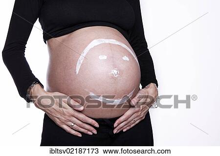 Stock Image - Baby belly with painted smiley face. Fotosearch