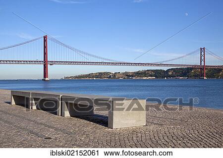Bench on the bank of the Rio Tejo River in front of the Ponte do 25 de Abril bridge in the district of Belem, Lisbon, Portugal, Europe View Large Photo Image Stock Image - Bench on the bank of the Rio Tejo River in front of the Ponte do 25 de Abril bridge in the district of Belem, Lisbon, Portugal, Europe. Fotosearch