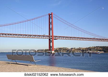 Bench on the bank of the Rio Tejo River in front of the Ponte do 25 de Abril bridge in the district of Belem, Lisbon, Portugal, Europe View Large Photo Image Stock Image - Bench on the bank of the Rio Tejo River in front of the Ponte do 25 de Abril bridge in the district of Belem, Lisbon, Portugal, Europe. Fotosearch