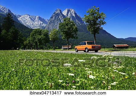Stock Photo - BMW 2002 tii, classic car on Eibseestraße in front of Zugspitze and Wank, Grainau, Upper Bavaria, Bavaria, Germany, Europe. Fotosearch