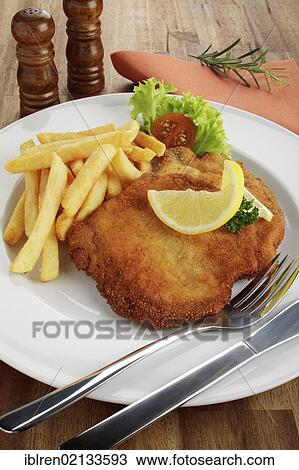 Stock Image - Breaded pork escalope Viennese style with lemon slice and French fries. Fotosearch