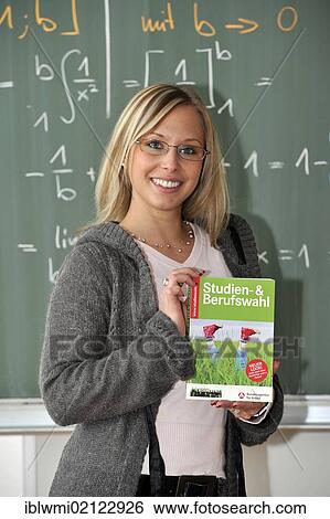 Stock Photograph - Career choice, mathematics, student, trainee teacher, prospective teacher, young teacher with study guide, blackboard, classroom, Baden-Wuerttemberg, Germany, Europe. Fotosearch