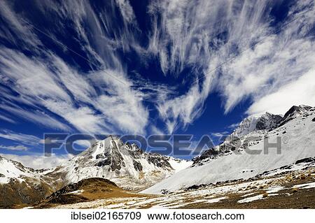 Stock Photo - Cloudy sky with snow-covered Andes Mountains, La Paz, Bolivia, South America. Fotosearch