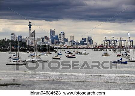 Stock Image - Dark thunder clouds above the harbour and skyline of Auckland, New Zealand, Oceania. Fotosearch