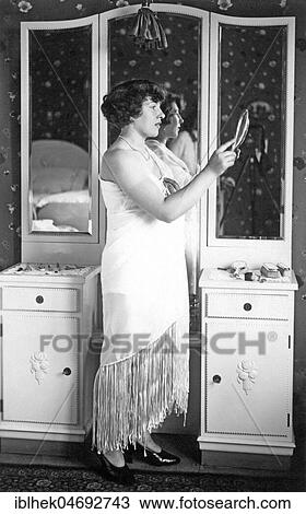 Stock Image - Fashion, Woman in Evening Dress stands in front of a Mirror, 1920s, Germany, Europe. Fotosearch
