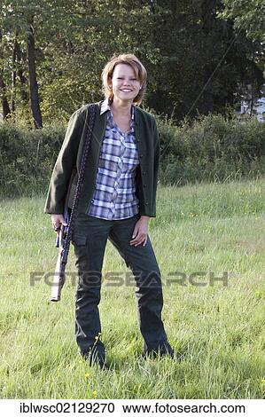 Stock Image - Female hunter with rifle wearing hunting clothes, Rhineland-Palatinate, Germany, Europe. Fotosearch