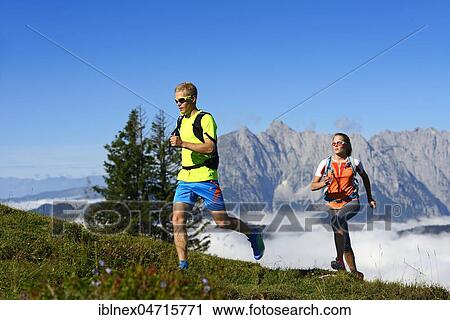 Stock Image - Hikers, Trail running on the Eggenalm, behind Wilder Kaiser mountain range, Reit im Winkl, Upper Bavaria, Bavaria, Germany, Europe. Fotosearch