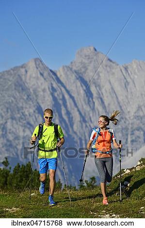 Stock Photo - Hikers, trail running on the Eggenalm, behind Wilder Kaiser mountain range, Reit im Winkl, Upper Bavaria, Bavaria, Germany, Europe. Fotosearch